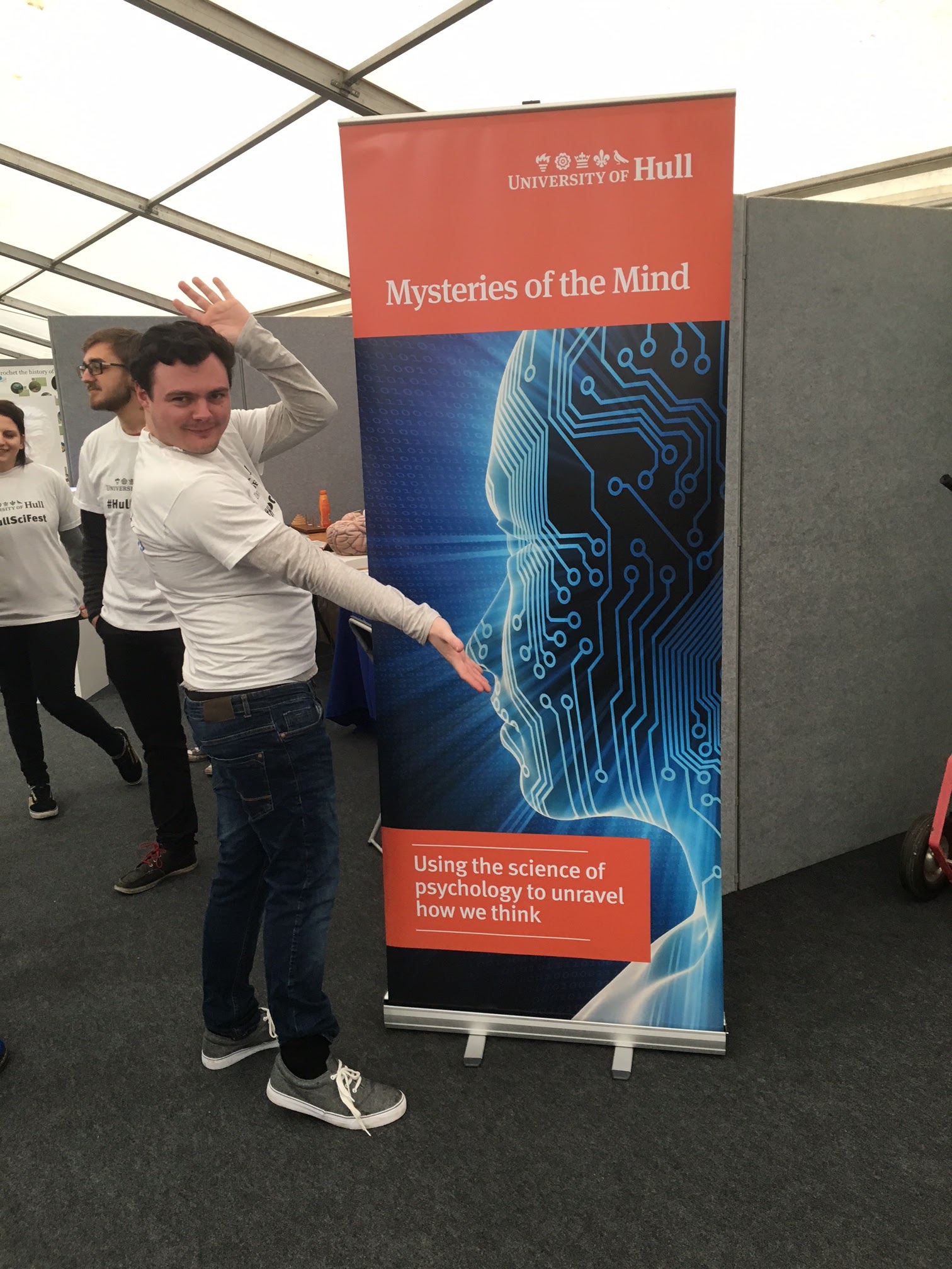 An outreach demonstrator beside the Mysteries of the Mind banner.