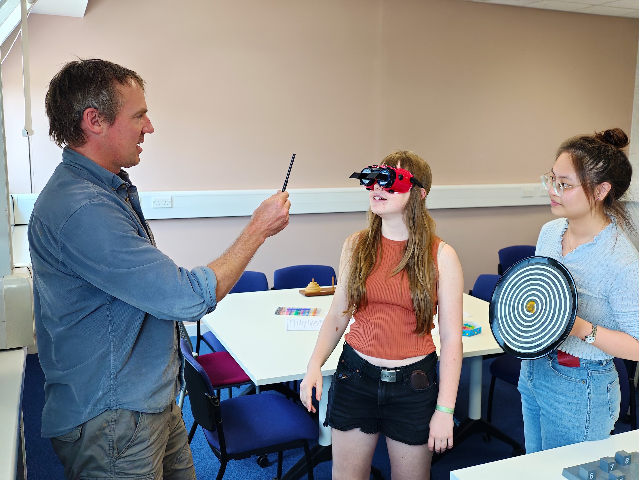 Demonstrating visual illusions with goggles and a spiral in a classroom.